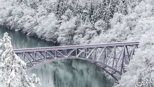 bridge over river in snowy forest